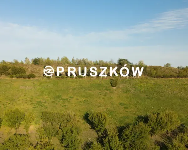 Napis "Pruszków" na tle zielonego wzgórza. Zastanawiasz się nad cenami mieszkań Pruszków?