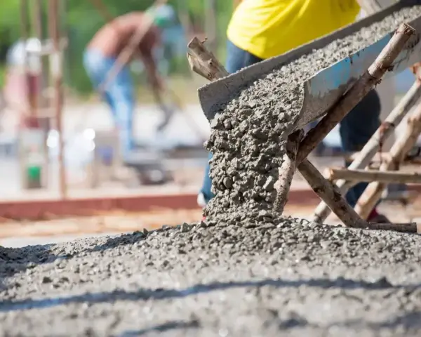 Betoniarka wylewa świeży beton. Zastanawiasz się, ile cementu na kubik betonu? Budowa trwa.