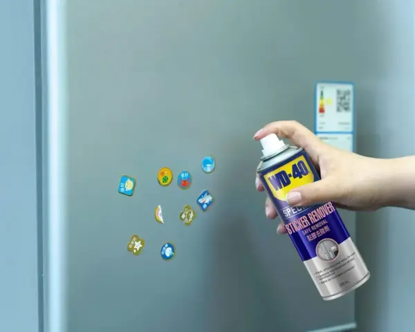 Jak usunąć naklejkę z szyby? Puszka WD-40 Sticker Remover w dłoni, gotowa do działania na lodówce.