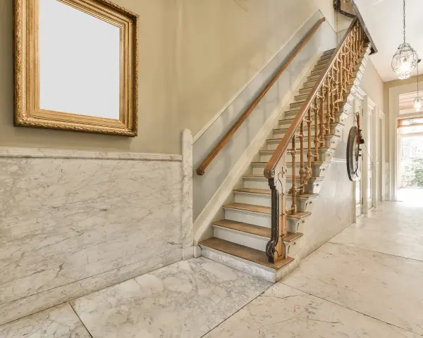 Elegante rellano de escalera comunitaria con mármol y un cuadro dorado. Ideas para decorar rellano escalera comunidad.