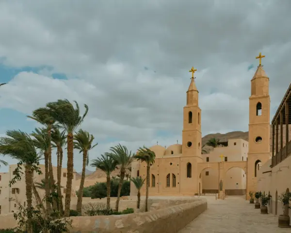 A monastery courtyard with palm trees and a bell tower, evoking the spirit of the desert fathers and mothers.