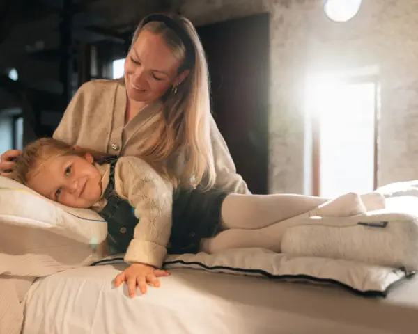 Mutter streichelt Kind, das auf einem Kissen liegt. Gute Nacht-Tipps für Kinder 11 Jahre.