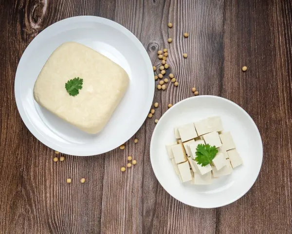 Kostka tofu i pokrojone w kostkę tofu na talerzach, gotowe do przygotowania pysznego tofu przepisu.