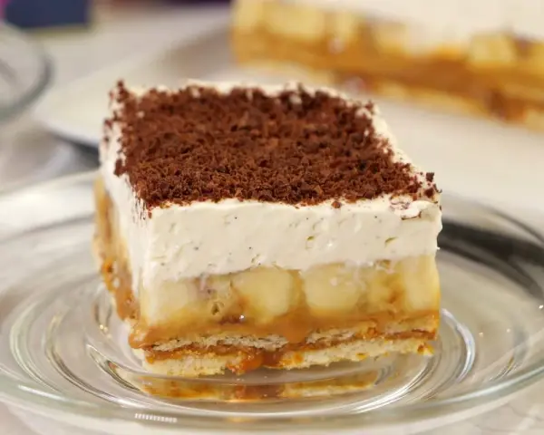 Pyszny kawałek Banoffee Pie z bananami, karmelem i bitą śmietaną, posypany czekoladą. Idealny przepis na deser.