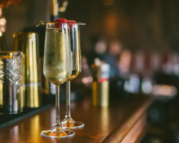 Dwa kieliszki musującego drinka z maliną na wierzchu. Idealne na domowe przyjęcie, inspiracja do drinki przepisy domowe.