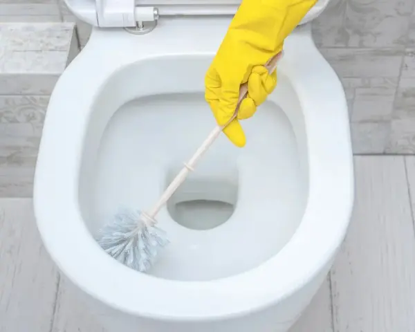 Main jaune pour nettoyer les toilettes.