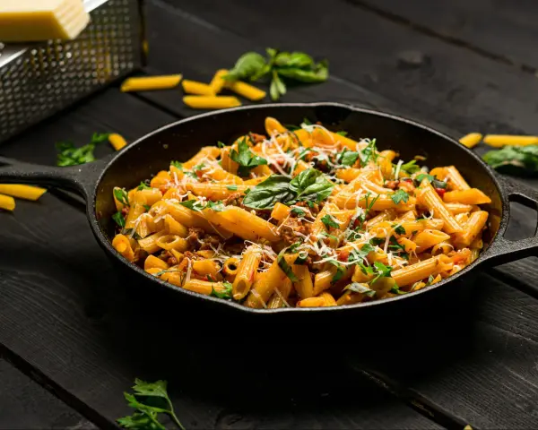 Makaron penne z mięsem mielonym i ziołami w żeliwnej patelni.