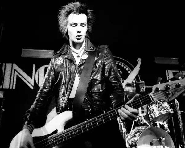 Sid Vicious, Punk-Ikone, spielt Bass auf der Bühne. Seine wilden Haare und Lederjacke unterstreichen seine rebellische Ausstrahlung. Seine Musik erfüllt die "sid wishes" des Publikums.