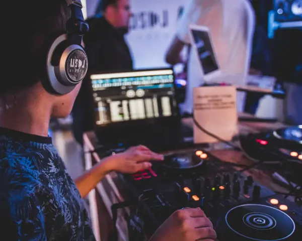 Młody DJ ćwiczy na sprzęcie, słuchawki na uszach. To świetny moment na rozpoczęcie kursu DJ online i naukę miksowania.