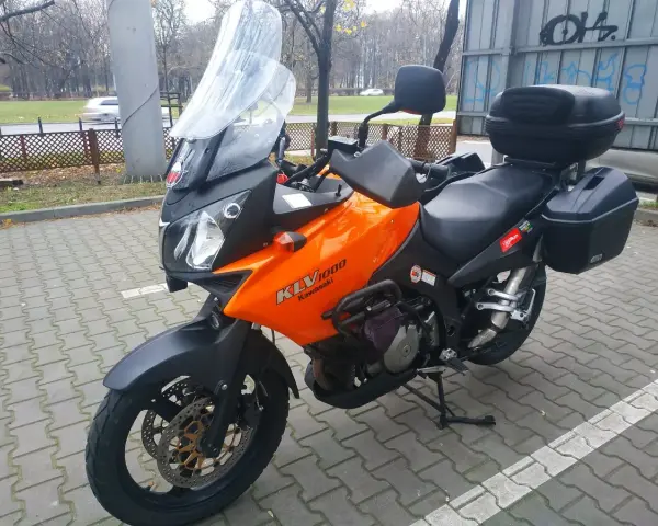 Pomarańczowy motocykl turystyczny Kawasaki KLV 1000 z kuframi, gotowy na przygodę.