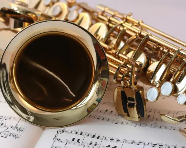 Ein glänzendes Musikinstrument, ein Saxophon, liegt auf Notenblättern. Seine goldene Oberfläche reflektiert das Licht.