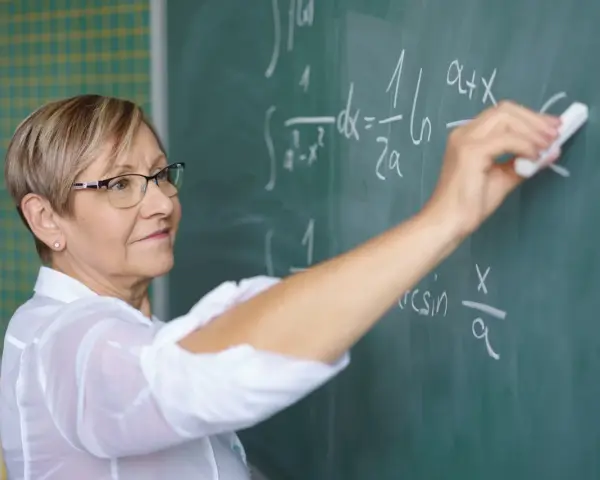 Nauczycielka matematyki pisze na tablicy wzory. Czy to zapowiedź podwyżki dla nauczycieli? Najnowsze wiadomości.