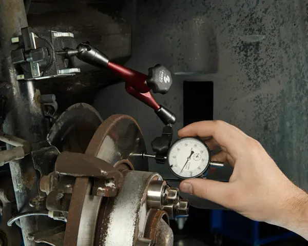Mechanik mierzy bicie przy hamowaniu tarczy hamulcowej za pomocą czujnika zegarowego.