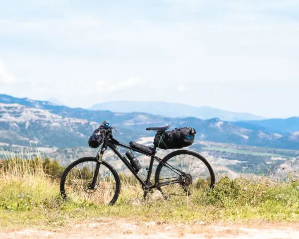 Rower gotowy do bike packingu, z sakwami na kierownicy i pod siodełkiem, na tle górskiego krajobrazu.
