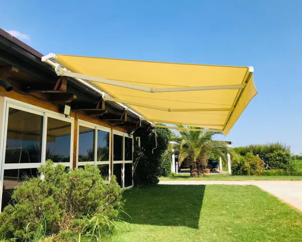 Tende da sole sconto in fattura, gialle e moderne, proteggono un edificio con ampie vetrate da un sole splendente.
