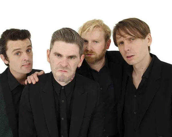 Les membres de Franz Ferdinand posent ensemble, quatre hommes aux regards intenses et aux coiffures stylées, prêts à enflammer la scène.