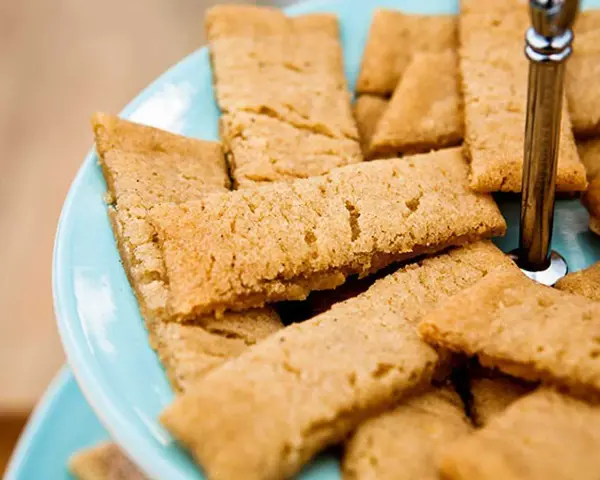 En hög med gyllene kolakakor på en ljusblå bricka. Perfekt för ett enkelt kolakakor recept.