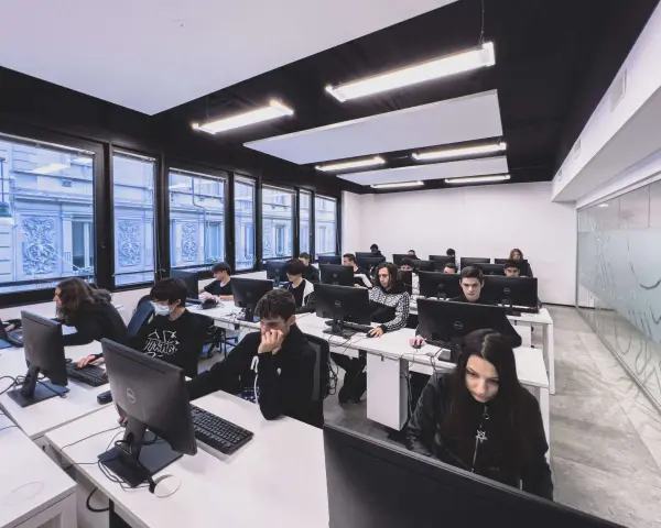Giovani studenti concentrati davanti ai computer, un'aula moderna che ospita un corso di programmazione gratis.