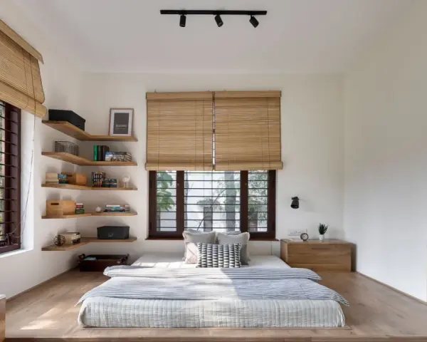 Habitación con cama baja, estanterías de madera y persianas de bambú. Un ejemplo de estilos de habitaciones minimalistas y acogedoras.