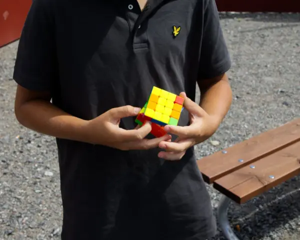 Ungdom med en färgglad Rubiks kub i händerna, redo för rubiks kub speed.