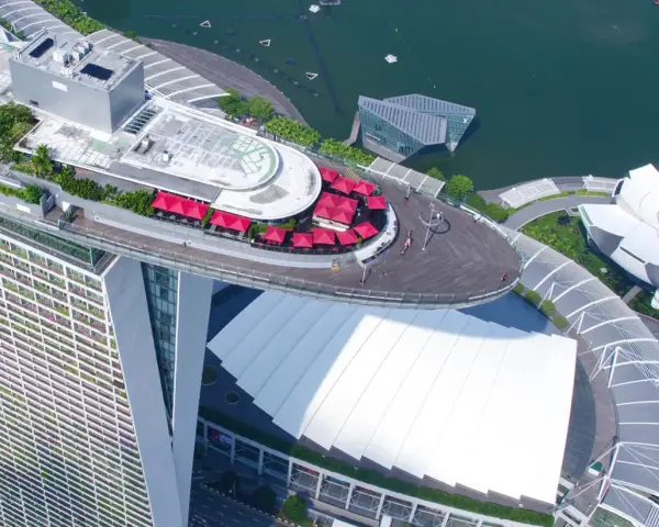 Widok z lotu ptaka na słynny singapur hotel statek z czerwonymi parasolami i basenem na dachu.
