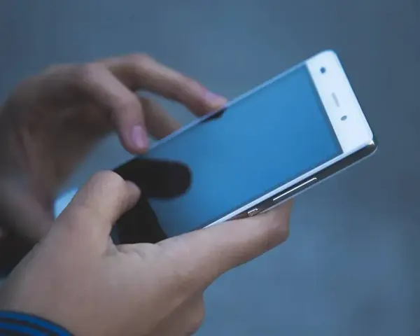 Dłonie trzymają smartfon, który może posłużyć jako telefon jako dowód w sprawie.