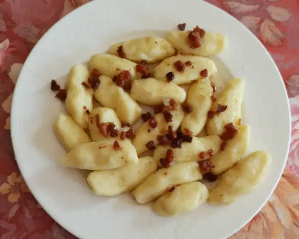 Kopytka z boczkiem, jak u babci! Pyszne ciasto na kopytka przepis babci, podane na talerzu.
