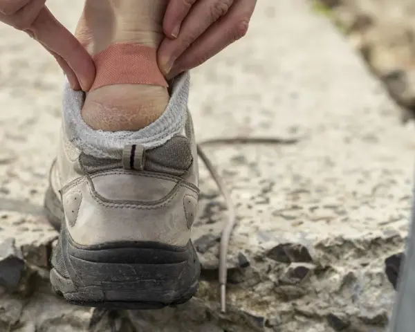 Application d'un pansement sur une ampoule au talon, une étape clé pour savoir comment soigner une ampoule au pied et continuer sa marche.