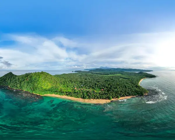 Zielona wyspa z palmami i plażą, otoczona turkusową wodą. Widok na Sao Tome z lotu ptaka.