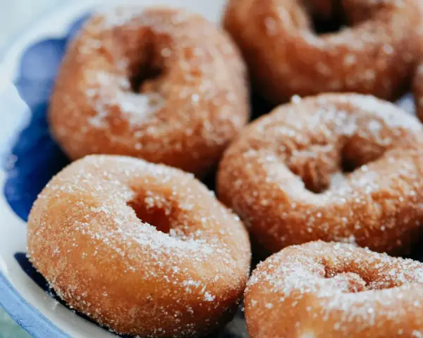 Rosquillas caseras de toda la vida, doradas y espolvoreadas con azúcar, listas para disfrutar.