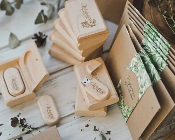 Drewniane pendrive'y z grawerem "Wedding" i koperty z motywem roślinnym. Personalizowane upominki dla gości od pary młodej to klucz do sukcesu.