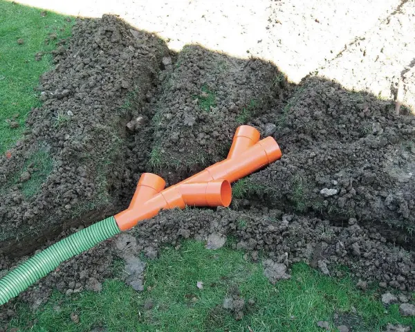 Tubi arancioni a Y e un tubo verde in una trincea: il sistema per capire come drenare il terreno.