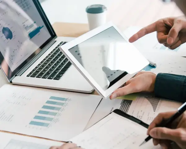 Analyse de rapports financiers sur tablette et ordinateur portable, illustrant la gestion administrative d'une entreprise.