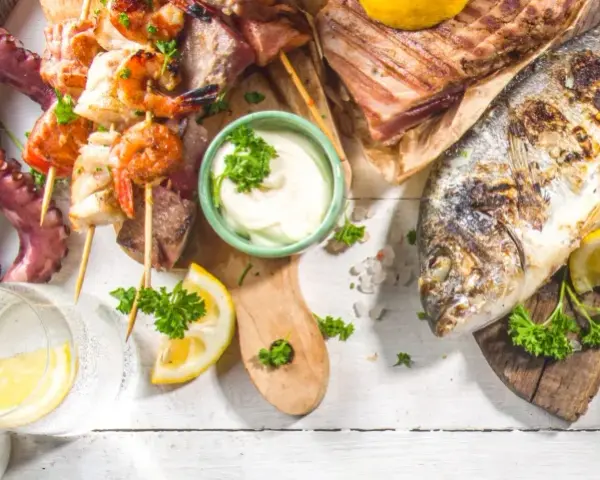 Un'abbondante grigliata di pesce con polpo, gamberi, calamari, aragosta e pesce intero, guarnita con limone e prezzemolo.