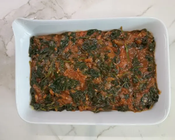 Lasaña de espinacas en salsa de tomate en un plato blanco.
