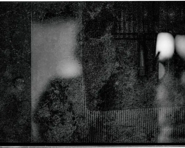 Mroczna, ziarnista fotografia. Widać fragmenty twarzy, być może portret autorstwa Mariusza Gajewskiego, z rozmytymi światłami i teksturami.