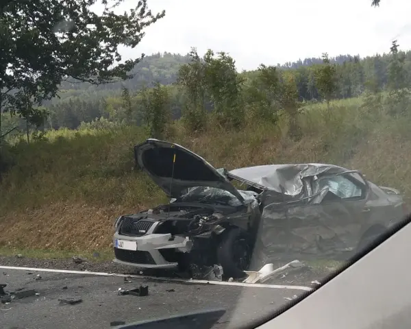 Zniszczony samochód po wypadku, maska otwarta, widoczne uszkodzenia. DKL rejestracja widoczna na przodzie pojazdu.