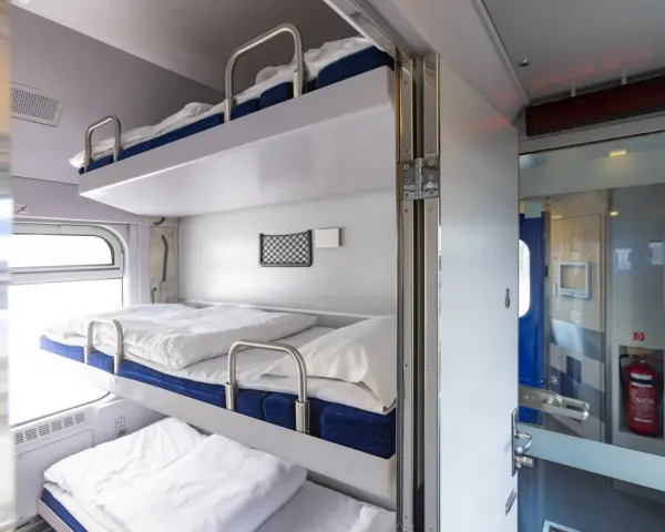 Wygodne łóżka w regiojet wagon sypialny. Trzy piętrowe prycze z pościelą czekają na podróżnych.