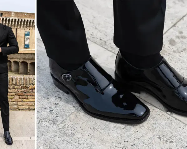 Uomo con vestito nero e camicia abbinata, indossa eleganti scarpe da abbinare in vernice nera.