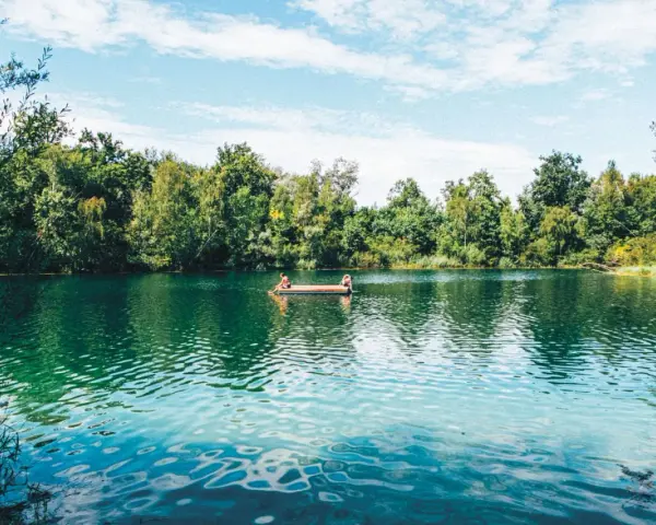 Zwei Personen entspannen auf einem Floß auf einem idyllischen Badesee im Schwarzwald.