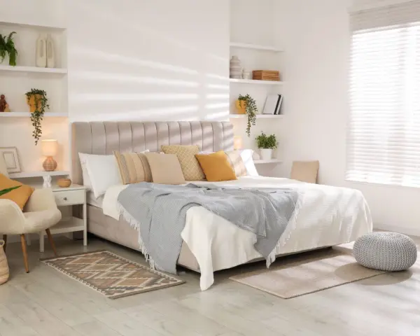 Dormitorios cálidos y acogedores con cama grande, sillón cómodo, plantas y estanterías decoradas.