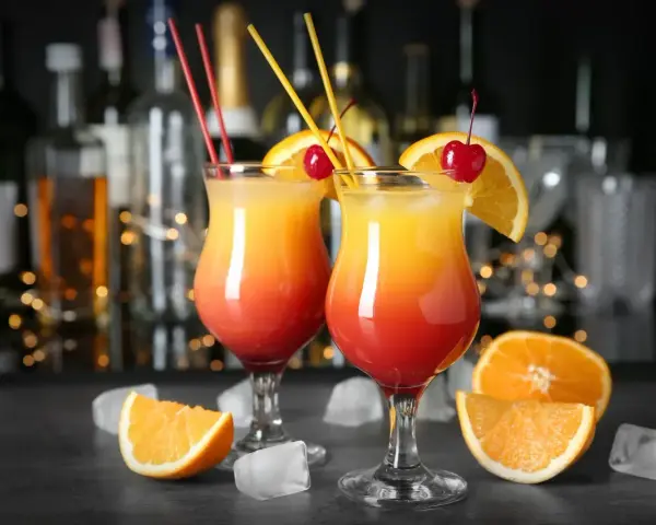 Dwa drinki ze spritem, ozdobione pomarańczą i wiśnią, na tle baru. Idealne na letnie wieczory.