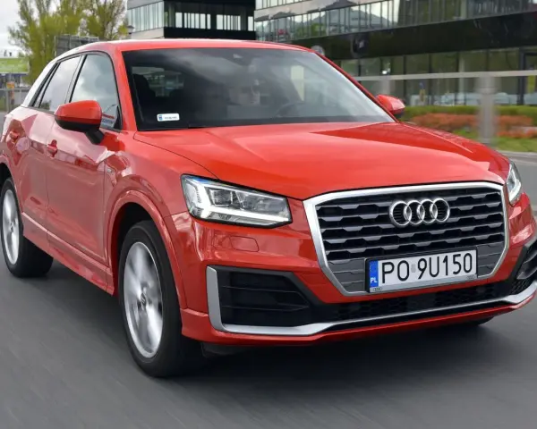 Czerwone Audi Q2 w ruchu miejskim. Choć jego design jest atrakcyjny, warto rozważyć potencjalne wady, takie jak ograniczona przestrzeń bagażowa.