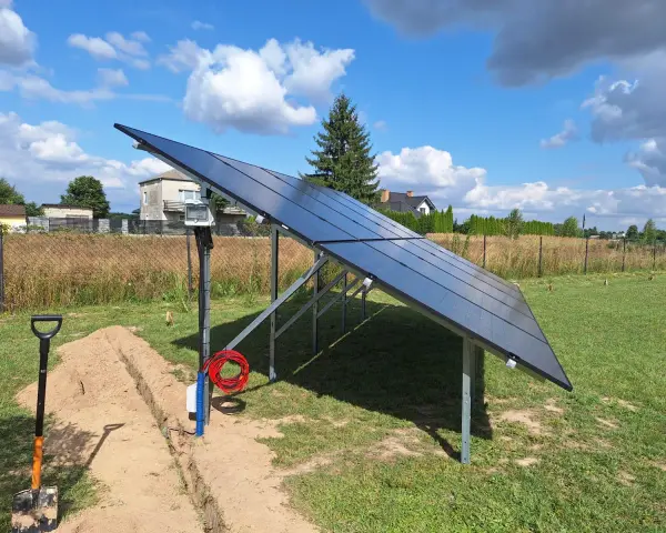 Nowa instalacja fotowoltaiczna w granicy działki, gotowa do podłączenia. Obok koparka i materiały.