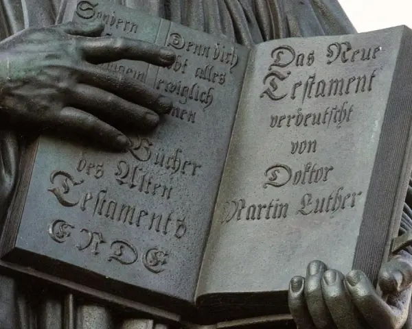 Hände halten ein aufgeschlagenes Buch mit Luthers Übersetzung des Neuen Testaments. Die Bedeutung der Reformation wird durch diese Darstellung greifbar.