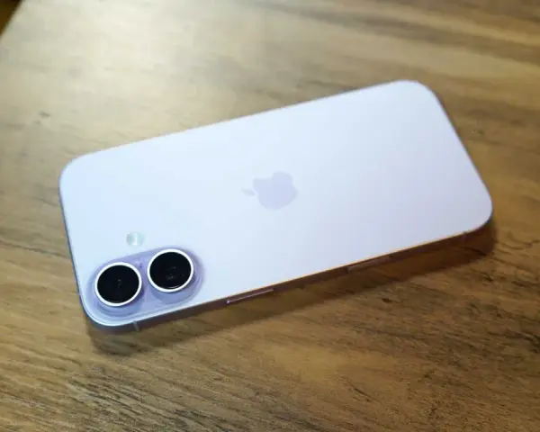 A light purple iPhone with a dual-camera system lies on a wooden surface.
