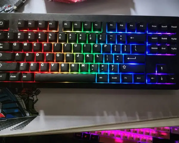 Eine schwarze Tastatur mit bunter RGB-Beleuchtung, die wie ein Regenbogen verstellt ist. Die Tasten leuchten in Rot, Orange, Gelb, Grün, Blau und Violett.