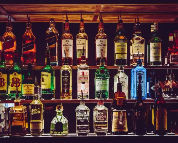 Różnorodne podstawowe alkohole do drinków: whisky, gin, tequila, likiery, stoją na półkach baru, gotowe do przygotowania koktajli.