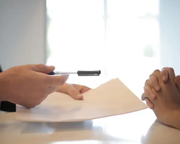 Man en traje entrega documento a persona con manos entrelazadas, discutiendo cómo devolver fianza alquiler antes finalizar contrato.