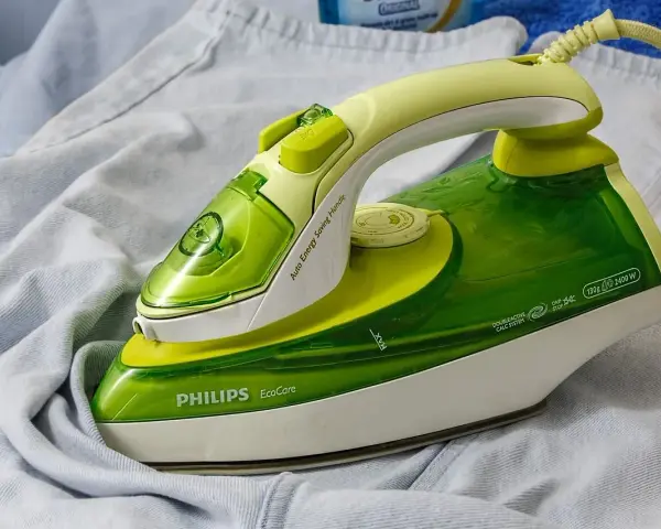 Ferro da stiro Philips EcoCare verde e giallo su un capo di abbigliamento. Non si vede a quanti gradi arriva il ferro da stiro.